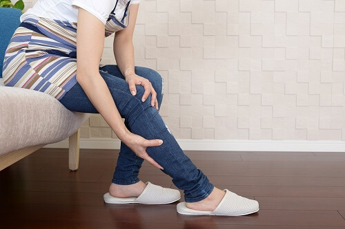 膝とふくらはぎをおさえる女性